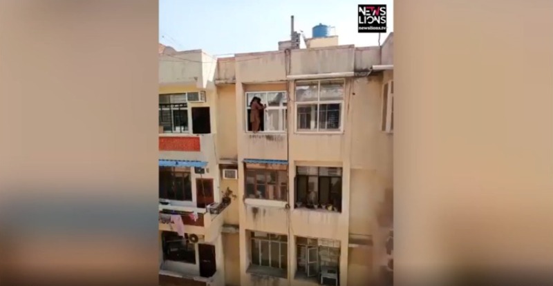 Woman cleans panes by balancing herself dangerously on window in northern India
